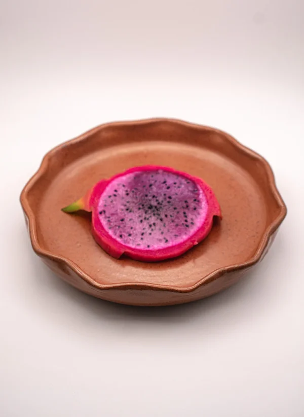 Plato de cerámica de diseño ondulado con esmalte color mole y presentación de pitahaya.