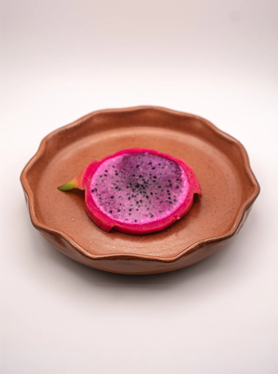 Plato de cerámica de diseño ondulado con esmalte color mole y presentación de pitahaya.