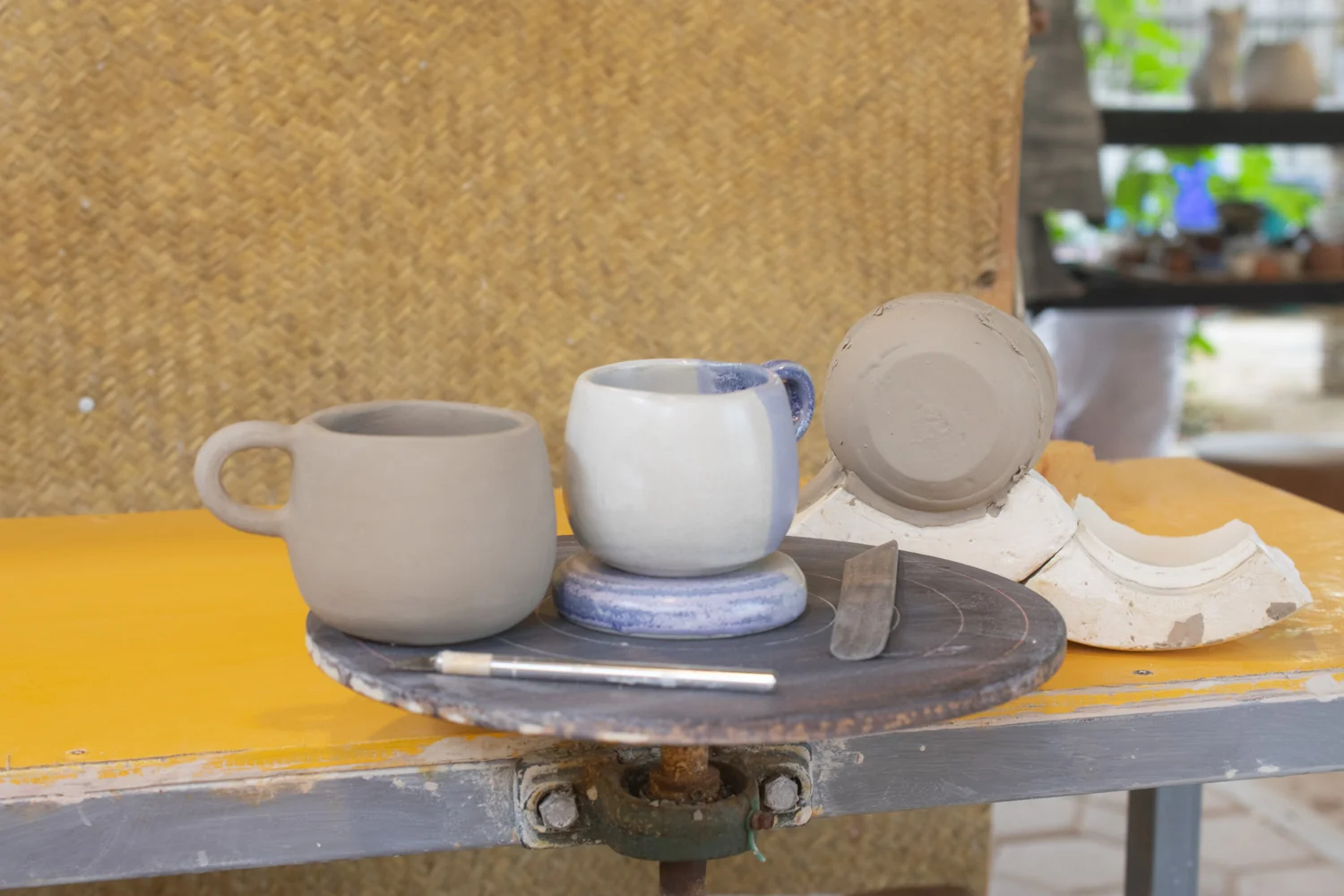 Taza de cerámica de alta temperatura en proceso de producción junto a su molde de yeso, con fondo de taller artesanal