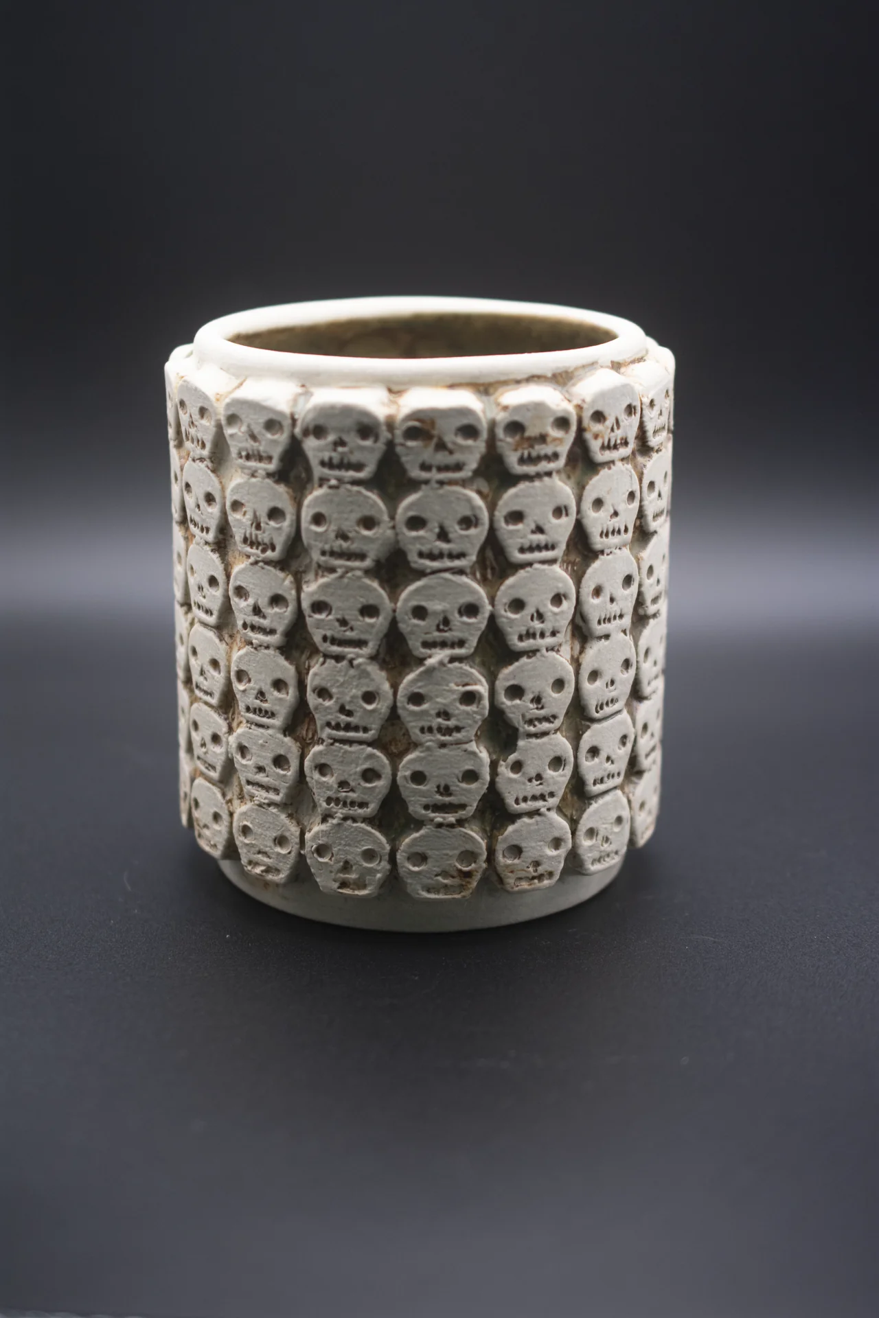 Vaso de cerámica artesanal con relieves de calaveras, inspirado en los tzompantlis mexicas.