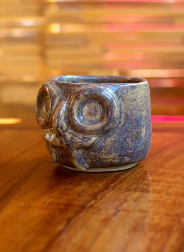 Taza de cerámica artesanal con rostro de Tláloc, esmalte tipo galaxia en tonos marrones y azulados.
